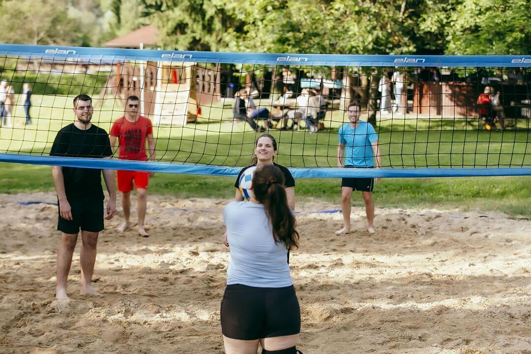 BE-terna employees playing beach volleyball during company event, emphasizing active team culture and employee well-being.