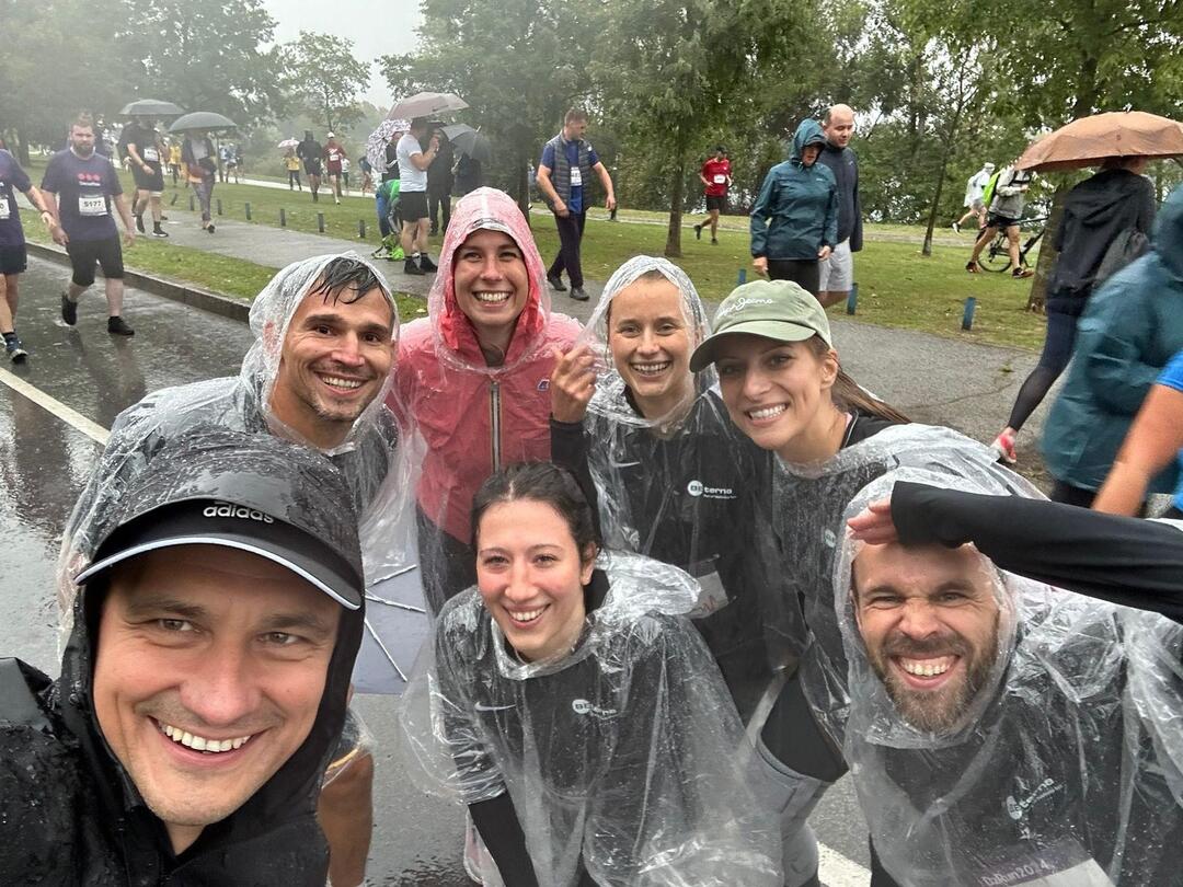 BE-terna team smiling in rain ponchos during company fun run, highlighting employee engagement and team spirit in all weather.