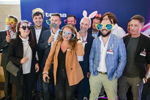 BE-terna employees having fun in photo booth with props during corporate event, showing vibrant company culture and team bonding.