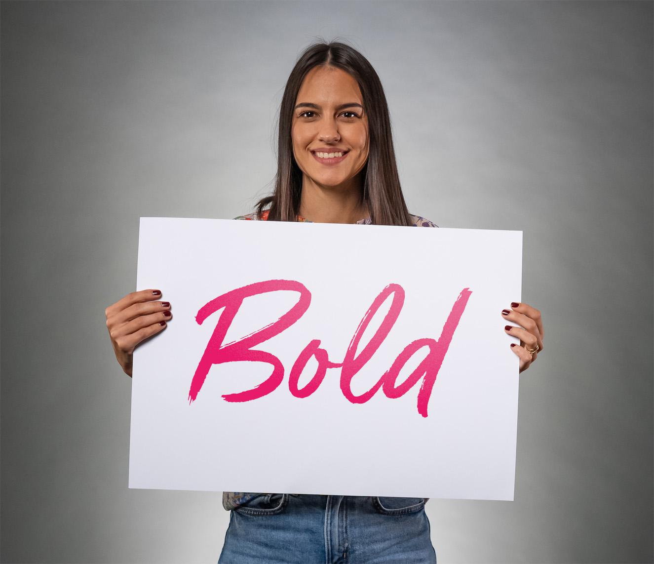 BE-terna team member holding “Bold” sign to represent company values and empowering IT career culture.