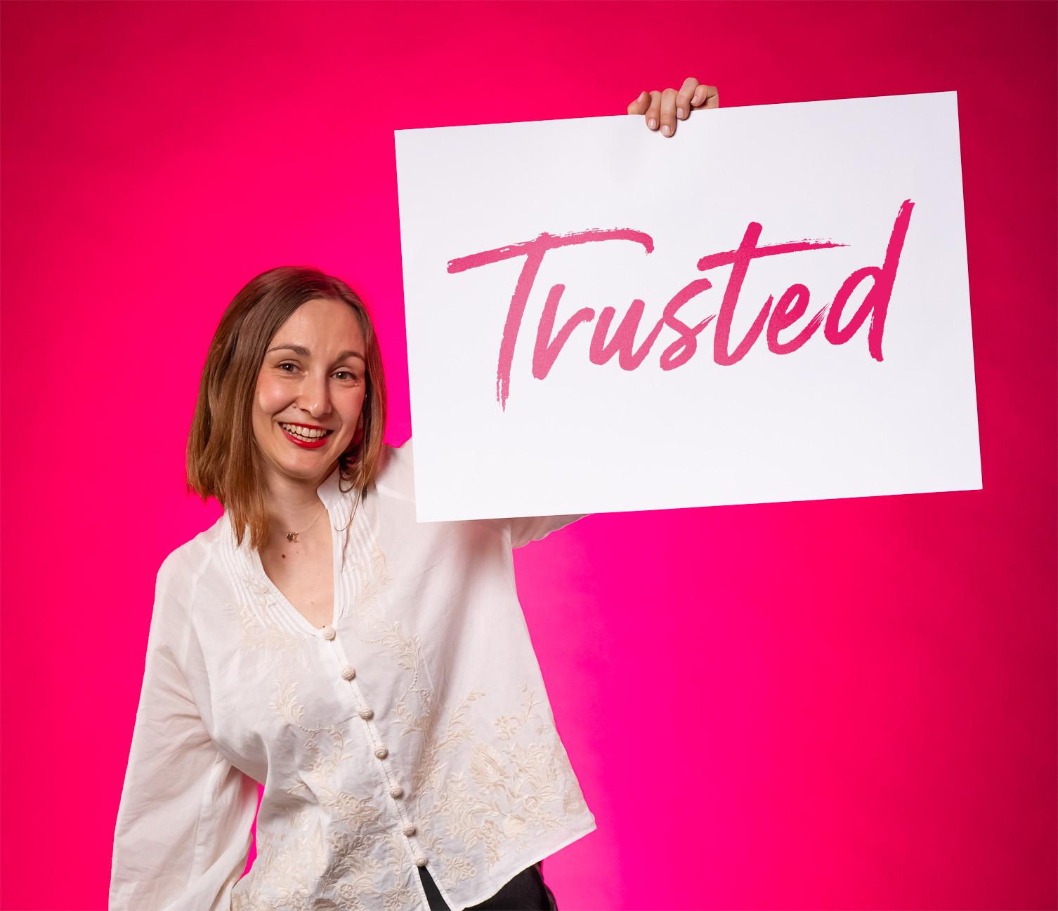 BE-terna employee holding “Trusted” sign reflecting company culture of reliability and strong employer brand in tech.