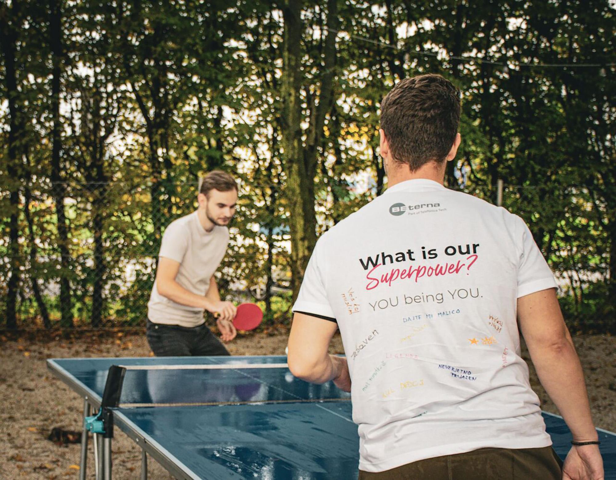 BE-terna colleagues playing table tennis outdoors during team event, promoting employee well-being and fun workplace culture.