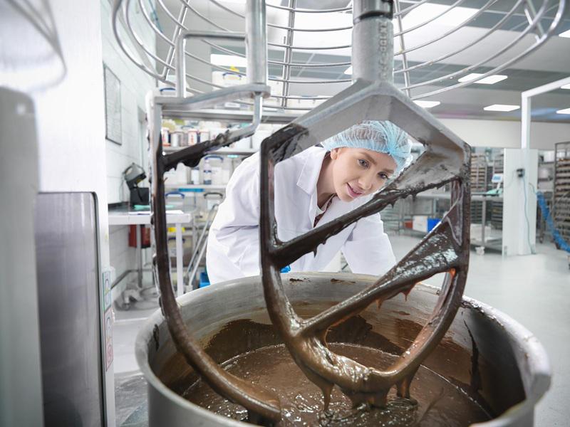 ERP-driven quality control and batch tracking in food production – technician monitoring industrial chocolate mixing